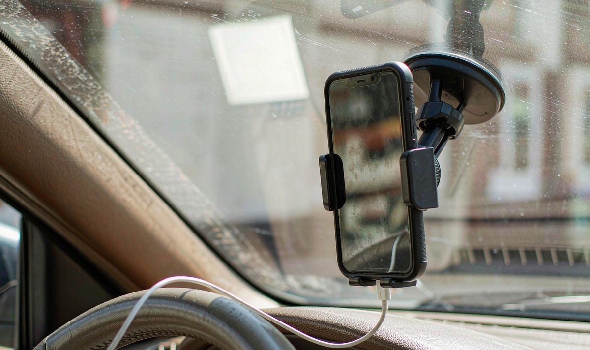 Phone left in a windscreen cradle under direct summer sun with its protective case still fitted and a charging lead connected to the bottom edge