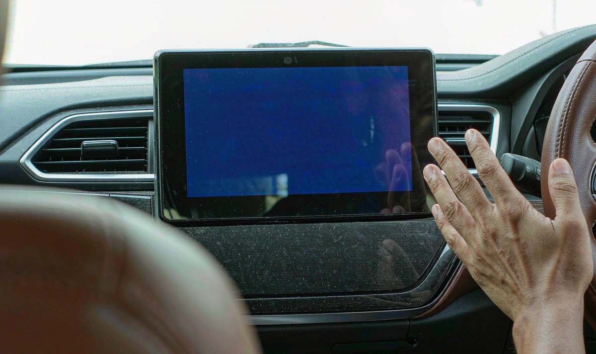 Aftermarket Android touchscreen head unit in a car dashboard frozen on its startup logo with the backlight lit and the touchscreen unresponsive