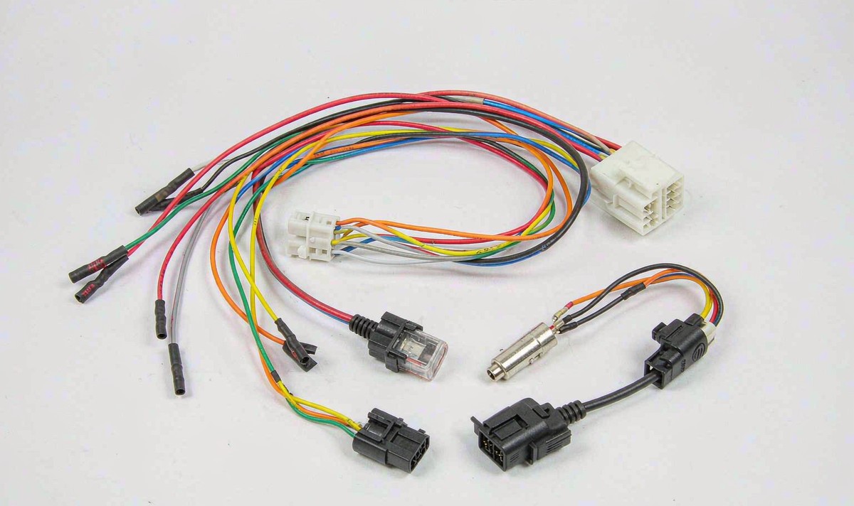 Car radio wiring harness laid out flat with a white 16-pin plug, an inline blade fuse holder, crimped signal leads and an antenna adapter cable
