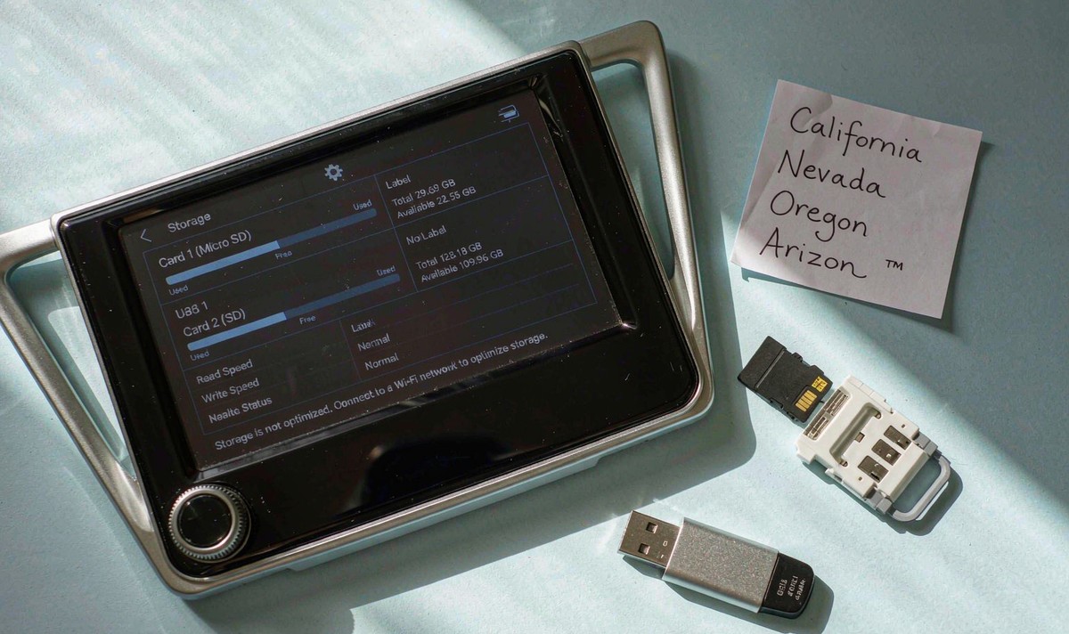 MicroSD card, USB drive and labelled paper notes on a bench beside a head unit showing internal and card storage usage bars