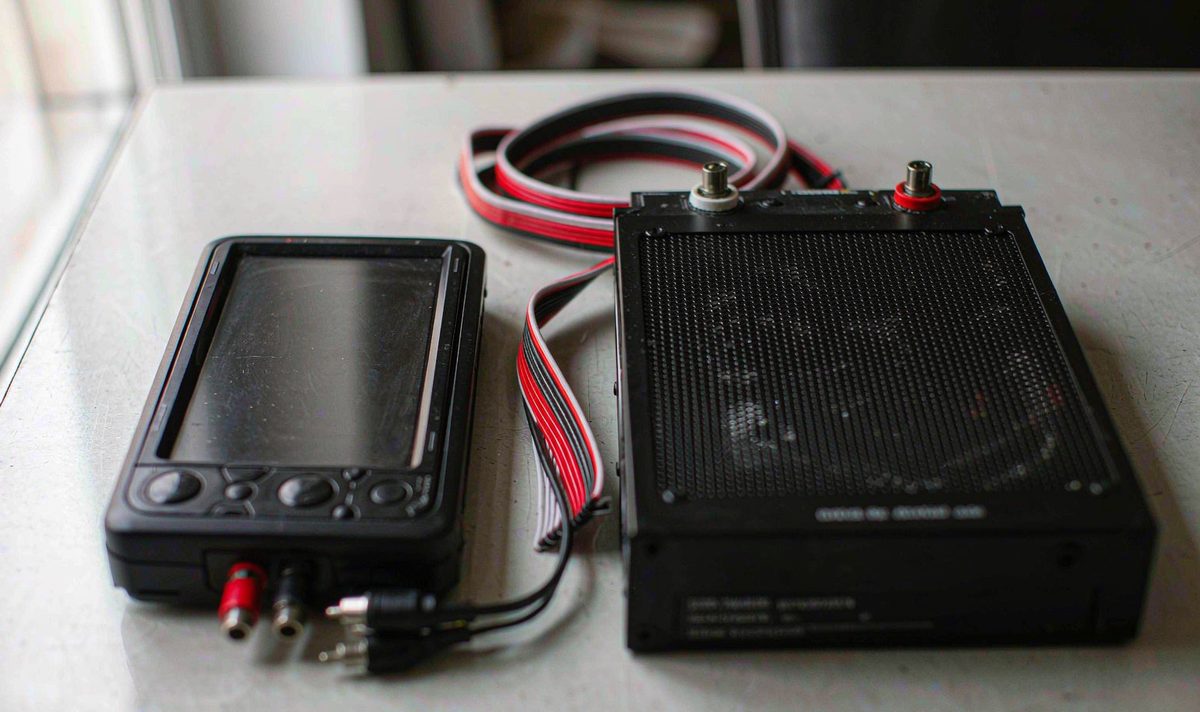 Head unit and amplifier connected by RCA signal cables on a workbench, with the power lead kept separate