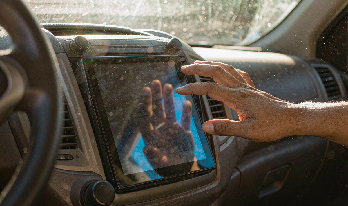 Dashboard surface heat car screen android head unit aftermarket dash kit, retain original factory features, a hand checking the warmth of a sunlight-baked car display