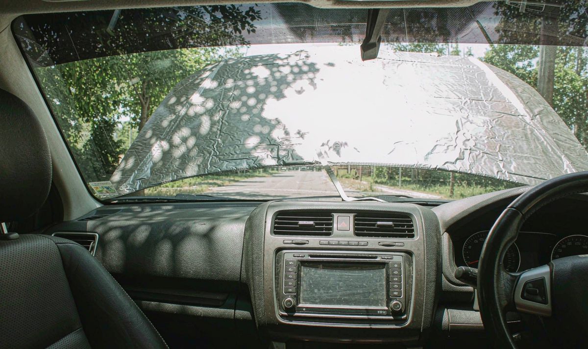 Sunshade over the glass car screen android head unit aftermarket dash kit, retain original factory features, a windscreen shade folded across a parked car stereo display