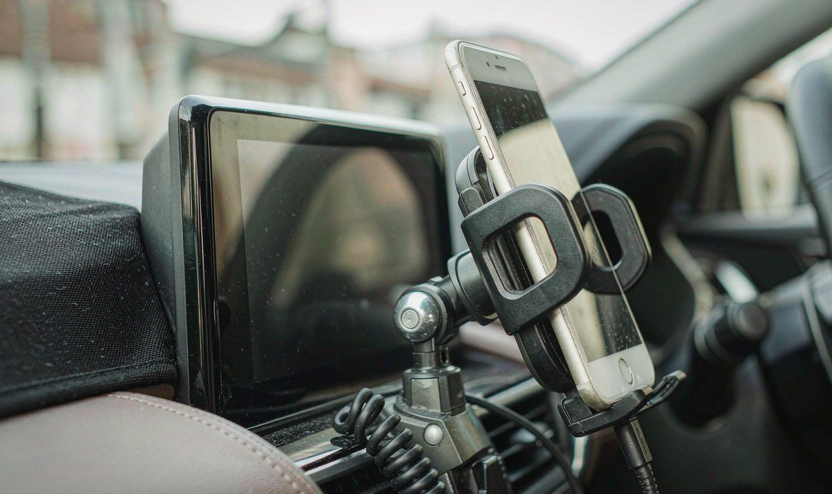 Phone in a cradle beside the centre console car screen android head unit aftermarket dash kit, retain original factory features