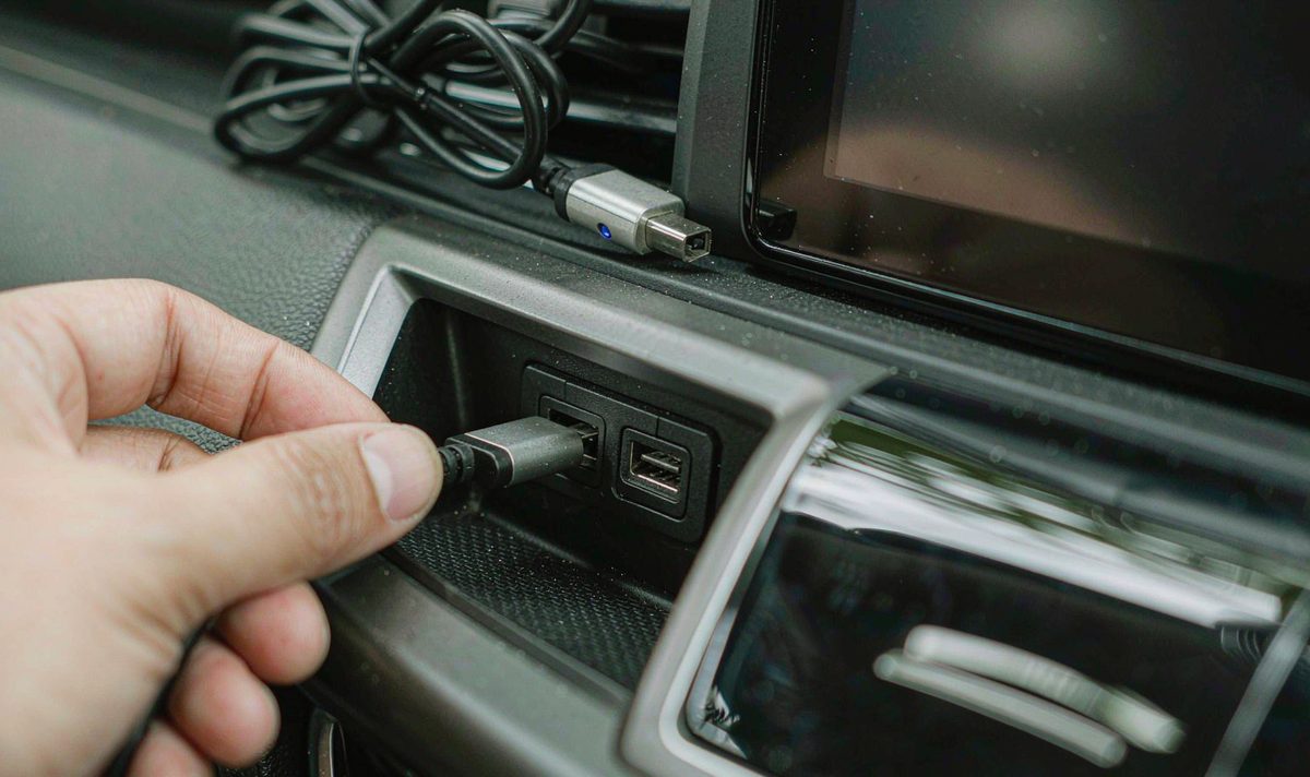Hand plugging a data cable into the car stereo console usb port android head unit dash kit, retain original factory features