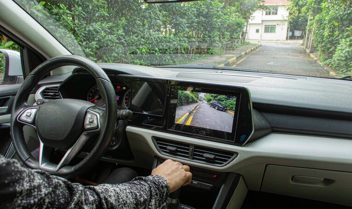 Dashboard car screen showing a reversing view android head unit aftermarket dash kit, retain original factory features, with a kerb line running along the left of the picture