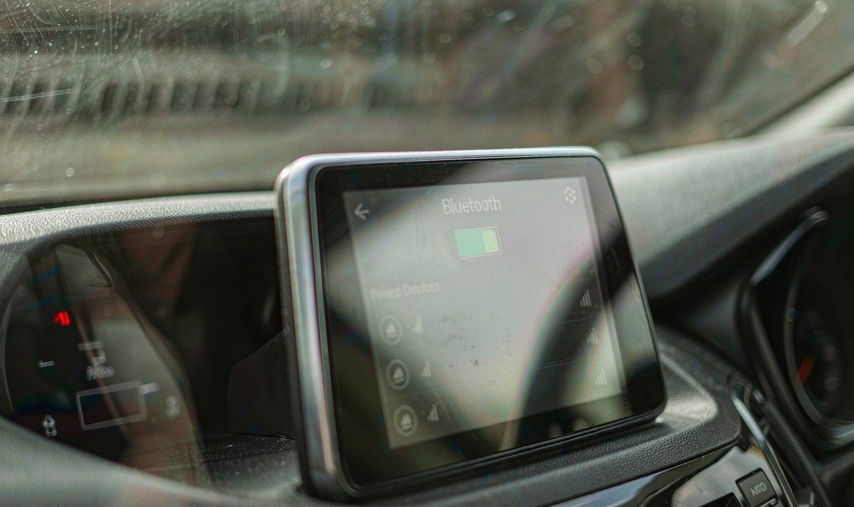 Retrofit android head unit screen in a car centre console with its Bluetooth settings page open and a short paired devices list on the glass, an android car stereo bluetooth pairing check