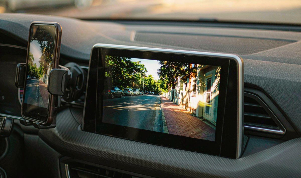 Retrofit car screen mirroring a film from a phone in a cradle, the two screens showing different moments, android head unit screen mirroring from phone