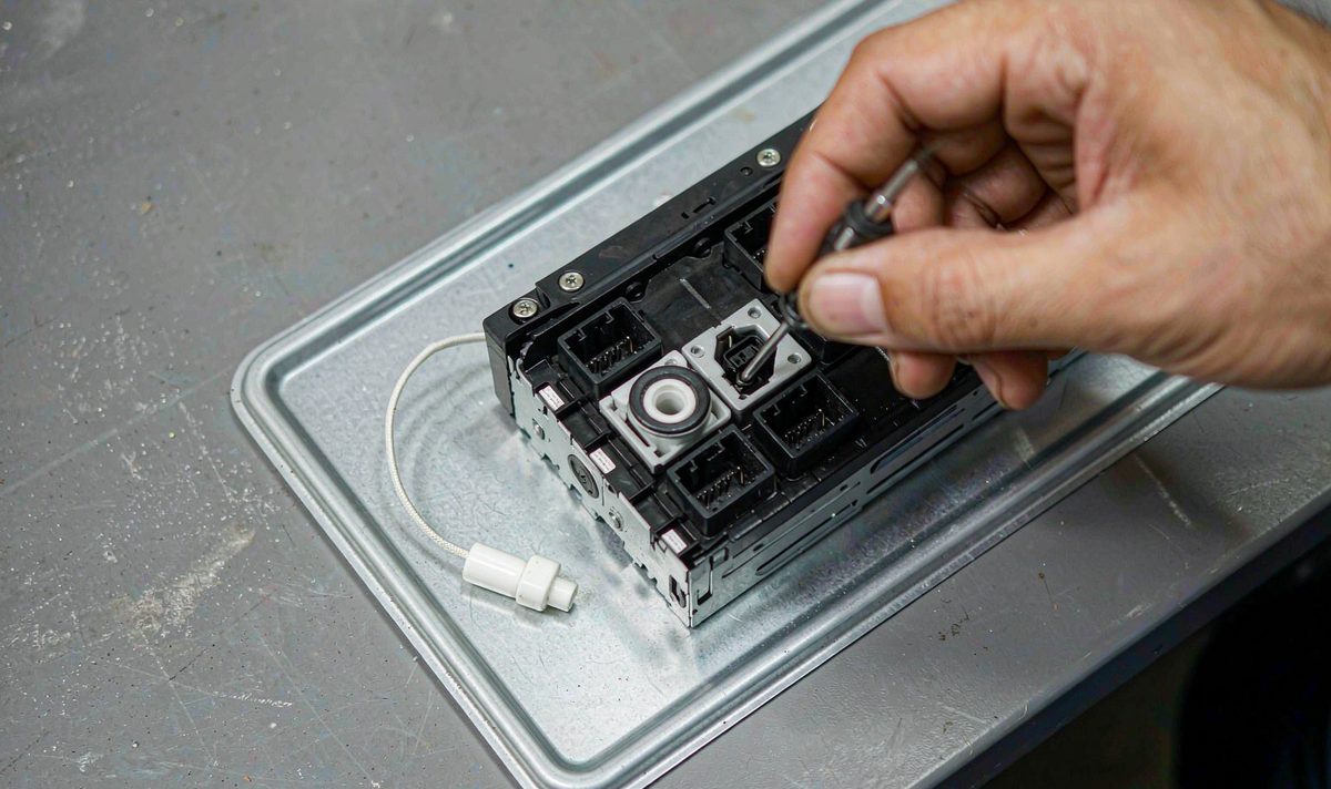 Back panel of an aftermarket head unit on a workshop bench with its thin Wi-Fi antenna wire and connector, car stereo antenna check