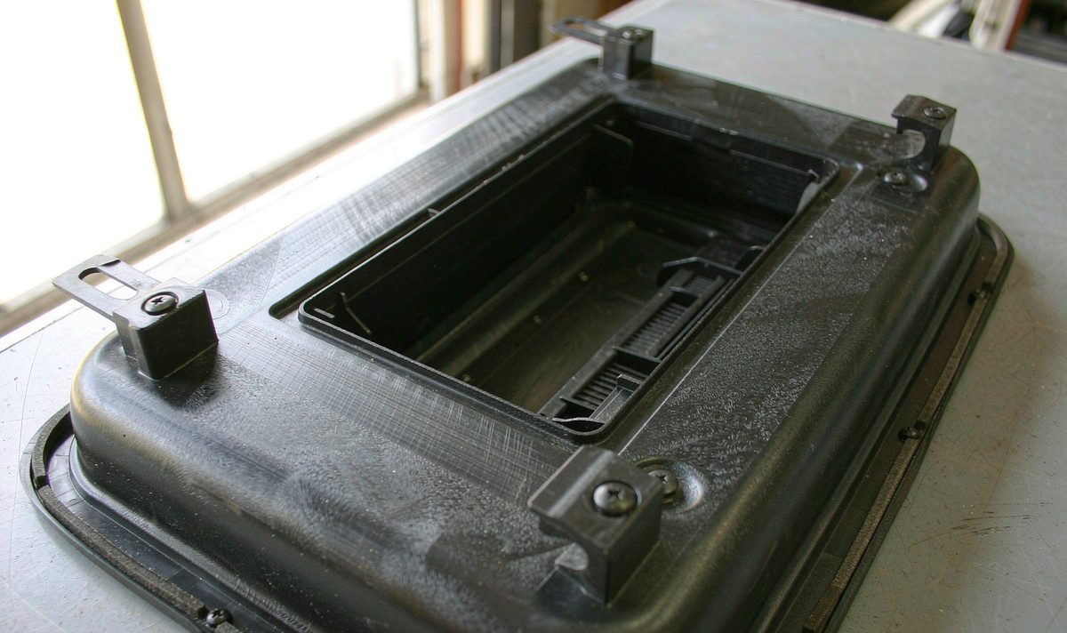 Back of a car dash fascia adapter panel for an aftermarket head unit, showing moulded side brackets, spring clips and screw bosses