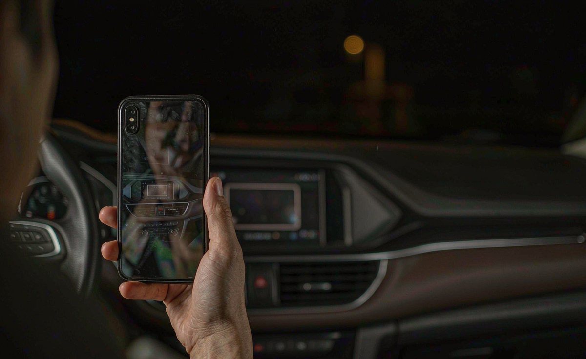 Driver photographing the windscreen with a phone to check the head unit screen reflection at night